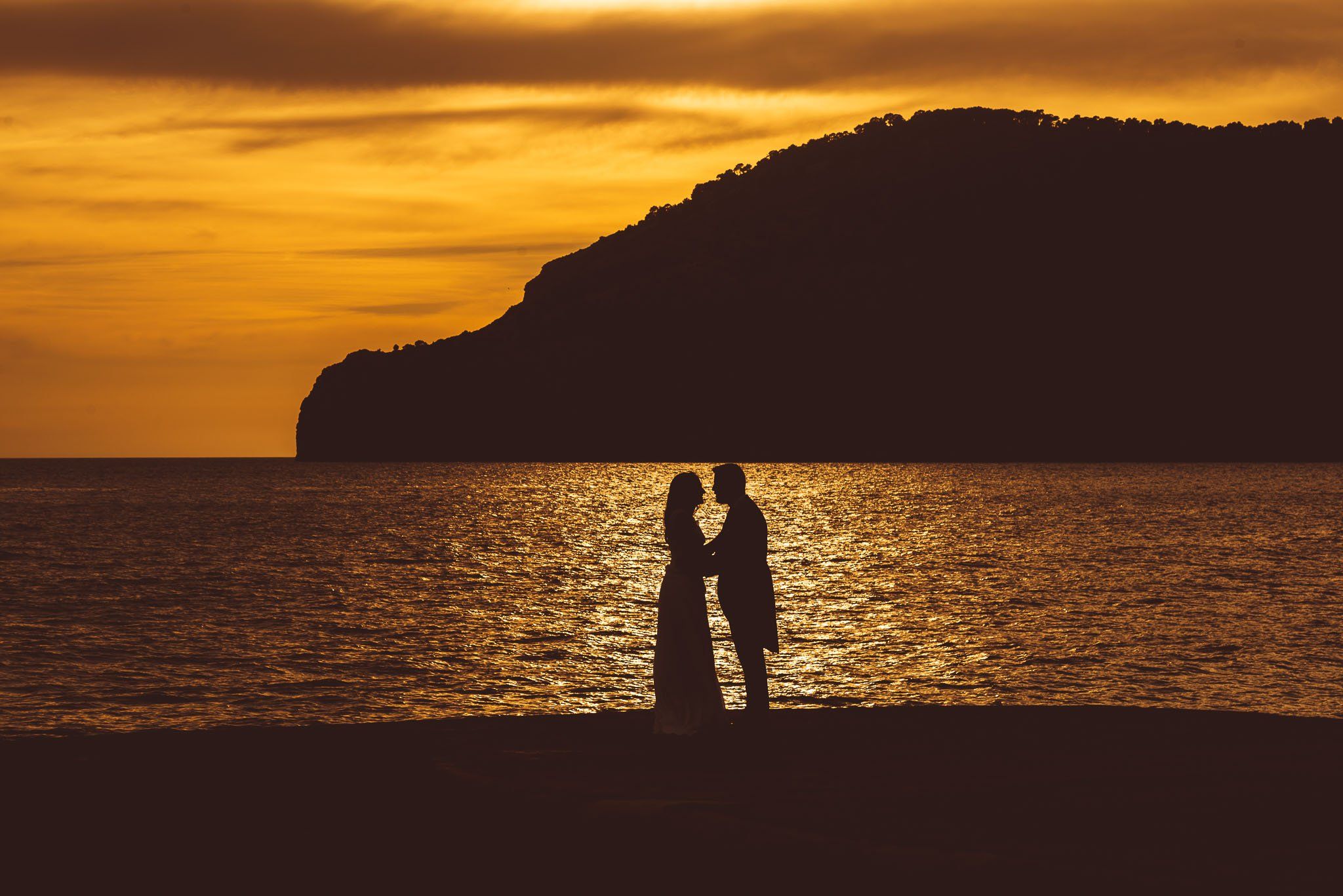 Pareja de novios a la puesta del sol en la playa